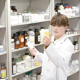 原料棚から薬を取り出す学生